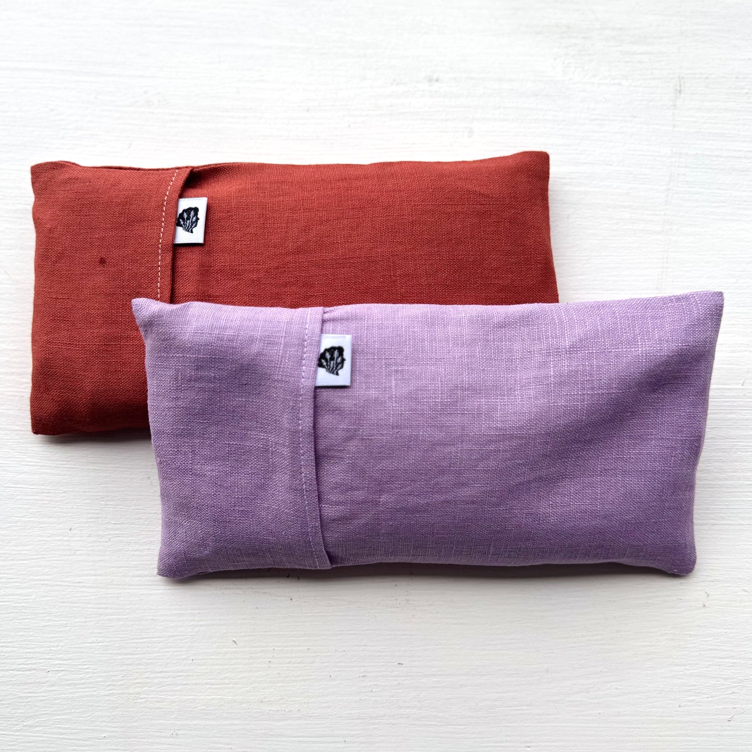 Purple and terra cotta eye pillows with white TLC tags
