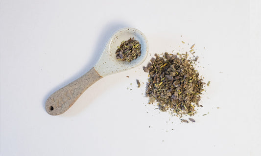 Small ceramic tsp with mixed ground herbs beside and in spoon