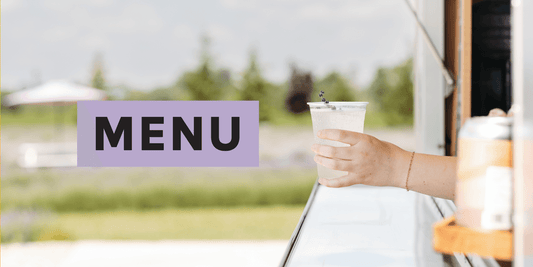 Menu with white woman's hand holding out a drink with a lavender stem in it
