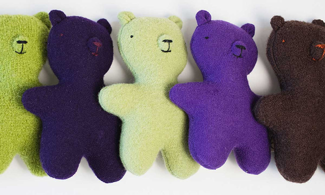 Small green, purple and brown teddies bears laying beside each other