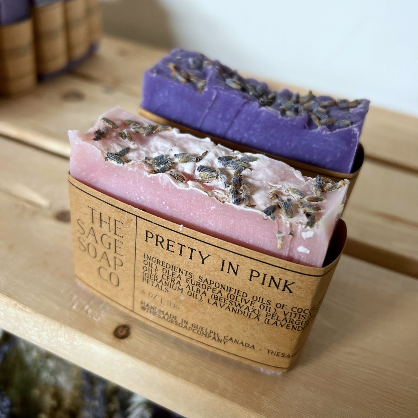 Two bars of soap, one pink and one purple, with lavender buds on top. Pink soap has a brown cardstock label with "Pretty in Pink" text
