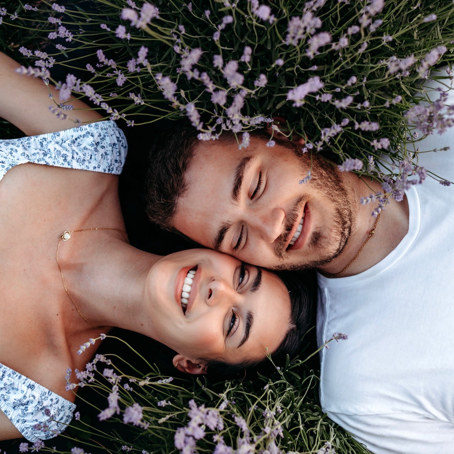Man and woman lay with faces together between two lavender plants