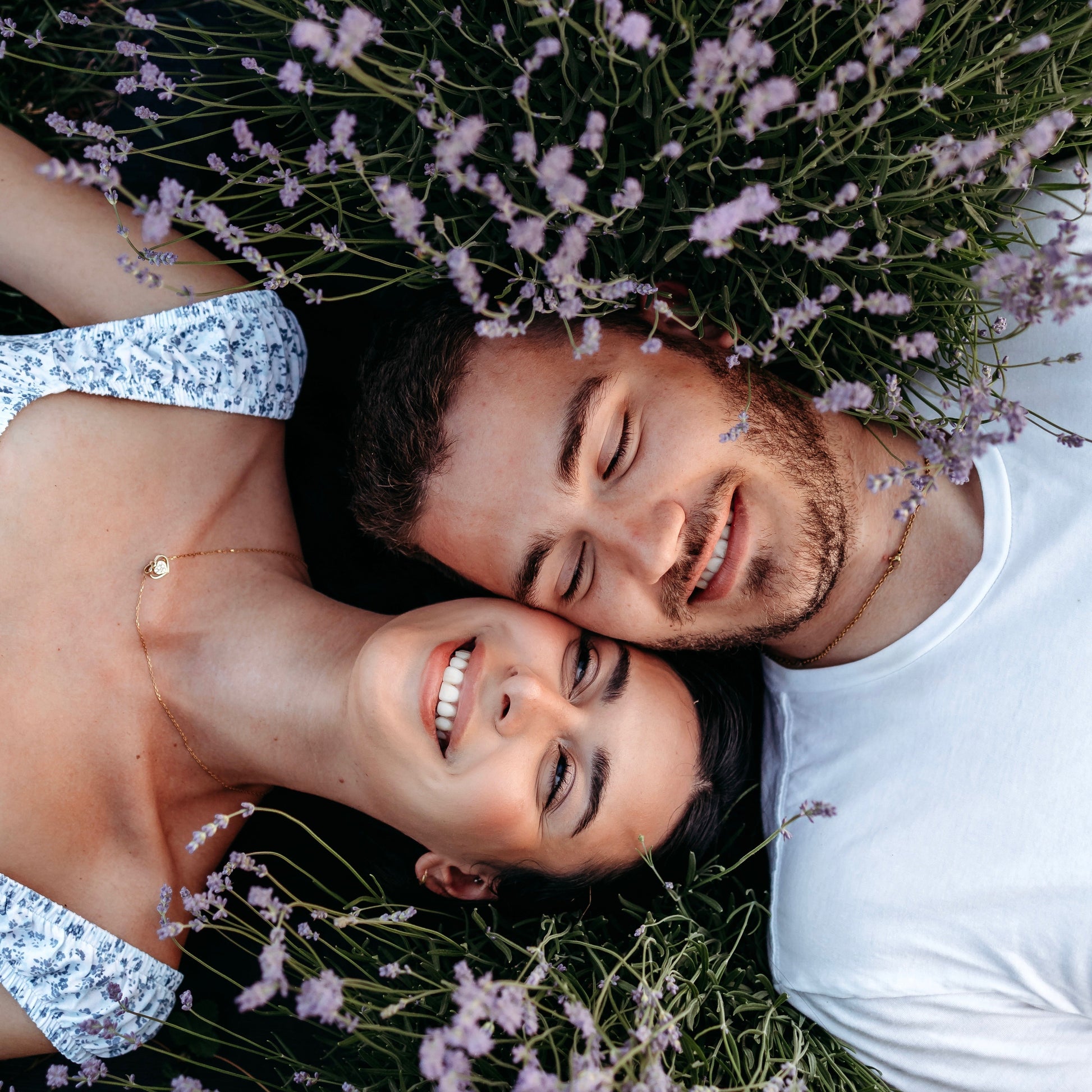 Man and woman lay with faces together between two lavender plants