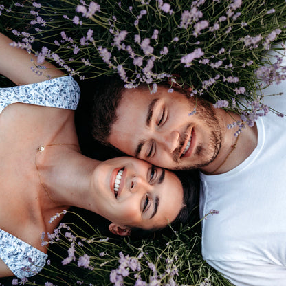 Man and woman lay with faces together between two lavender plants
