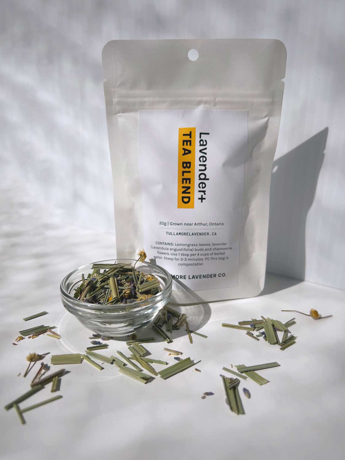 White bag with Lavender+ Tea Blend label and loose leaf tea in small glass bowl and on white table