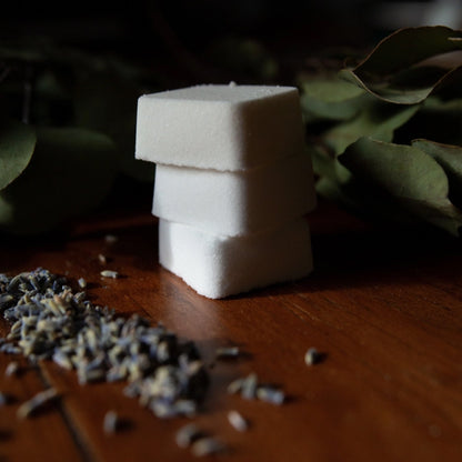 Stack of white shower steamers with lavender and eucalyptus in background.