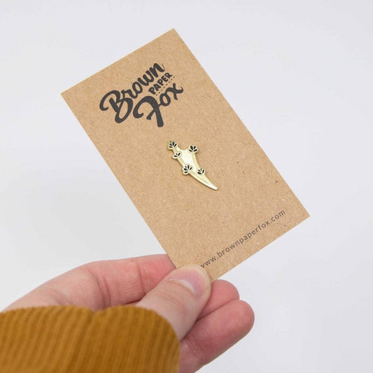 Hand holding brown paper with gold lavender pin on it