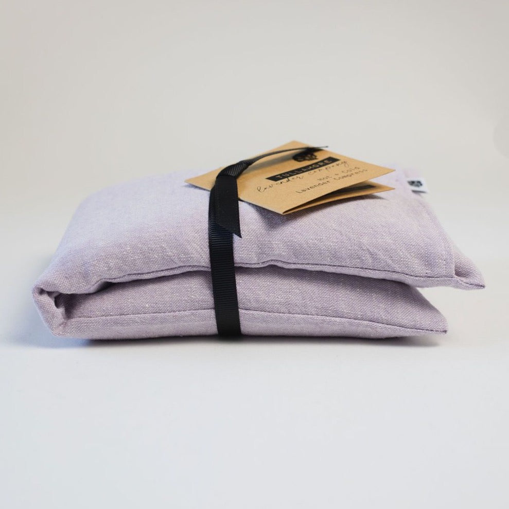 Purple linen compress folded with black ribbon and brown paper tag